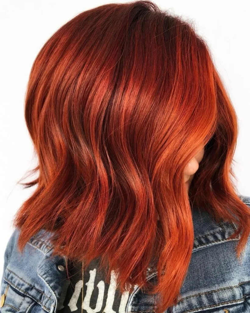A women in blue denim jacket showing the side view of her Bright Strawberry Red hair color A women in blue denim jacket showing the side view of her Bright Strawberry Red hair color - red hair color with highlights
