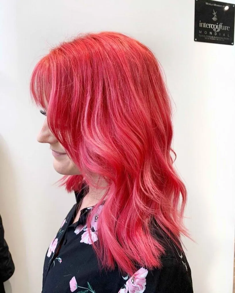 A women in black floral printed dress showing the side view of her Coral Red hair color A women in black floral printed dress showing the side view of her Coral Red hair color - dark red hair dye