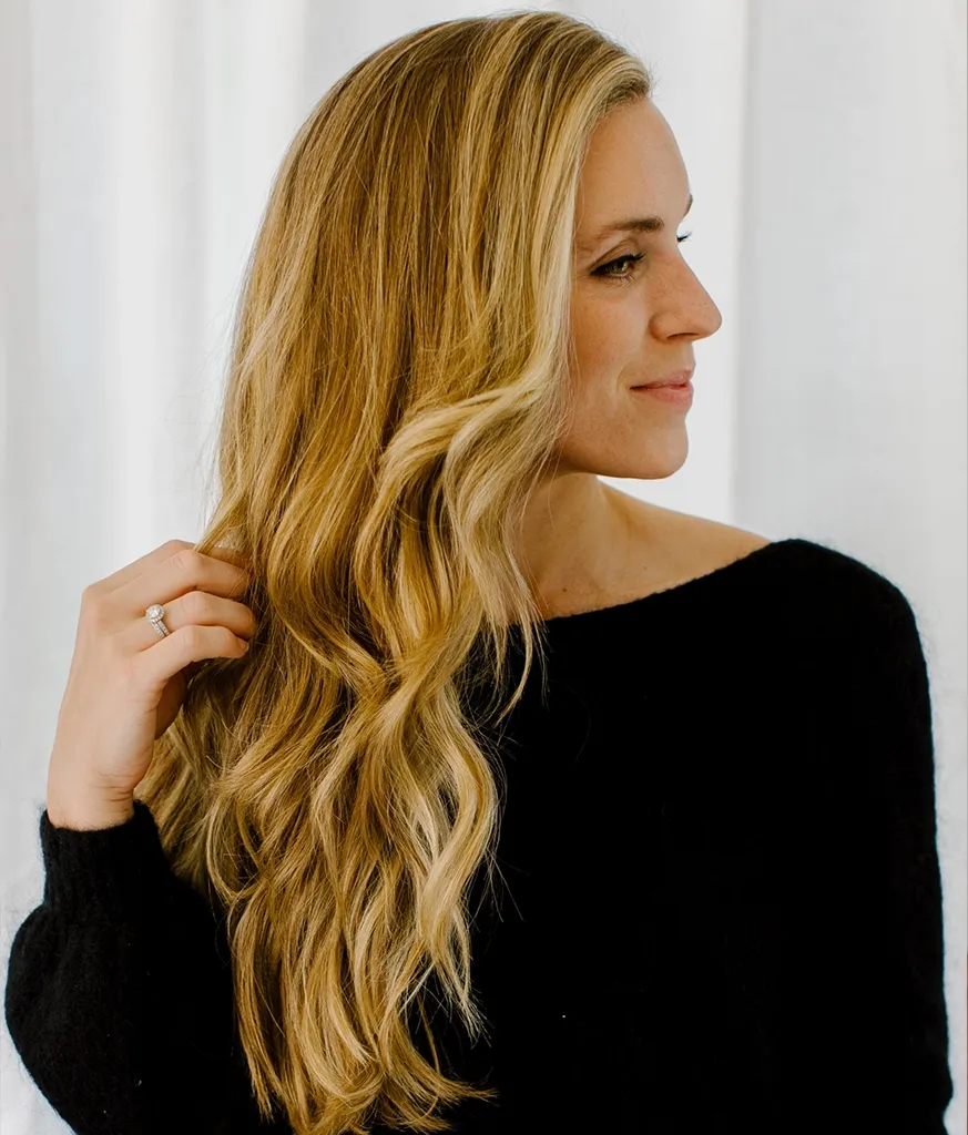 Woman in boat neck black dress showing the side view of her Lush Curls hairstyle Woman in boat neck black dress showing the side view of her Lush Curls hairstyle - long haircut for women