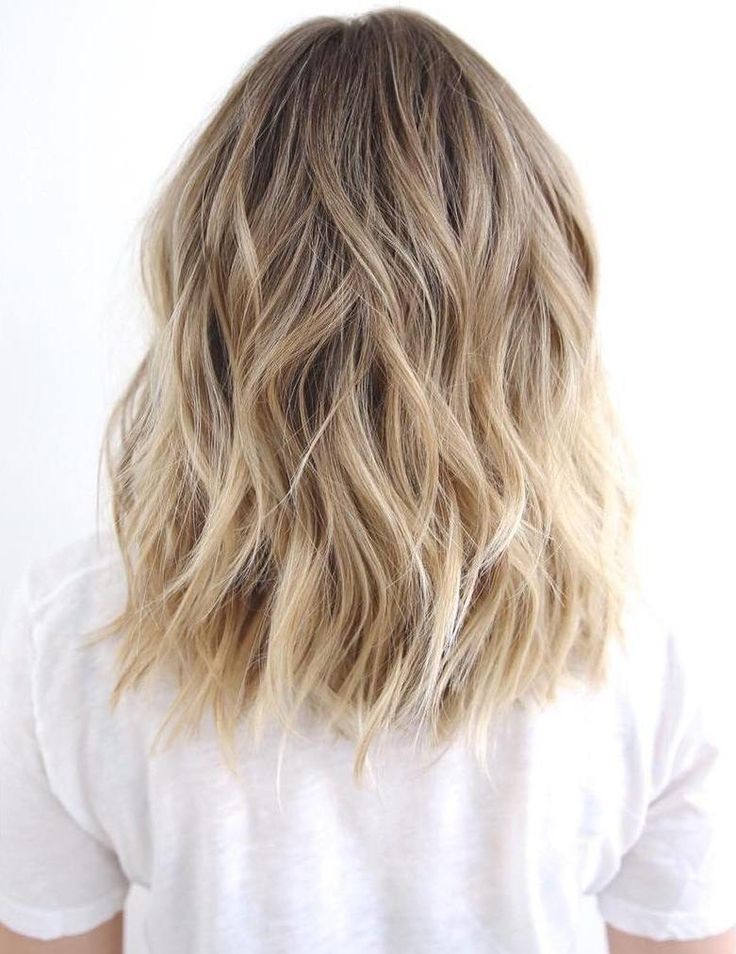 A woman in white t-shirt showing the back view of her Blonde Blayage Waves - hairstyles for girls with medium hair