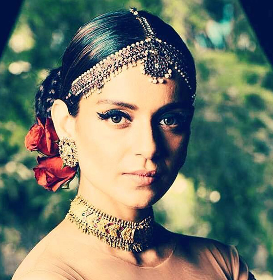 A girl in peach color blouse and heavy jewellery showing her senorita bun - bun hairstyles for Indian wedding