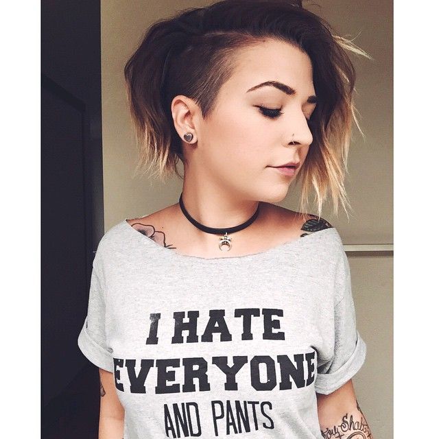A girl in grey top with lots of tattoos showing her Bob with shaved side - haircut Teenage Girls