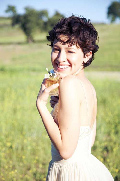 A smiling girl in multicolor deep neck top showing her curly pixie with bangs  - haircut Teenage Girls