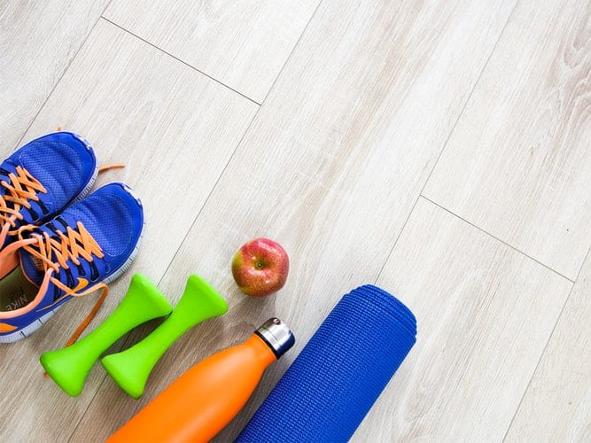 Blue sports shoes, bottle, mat and apple etc stuff is put up on the floor - household fitness 
