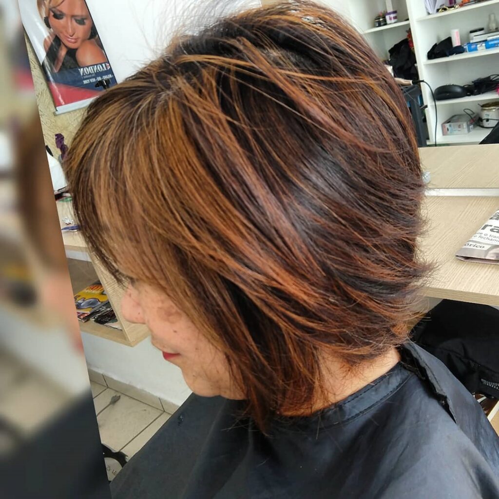 A women is showing side view of her cooper shimmer blonde hair color with side pose - short hair color