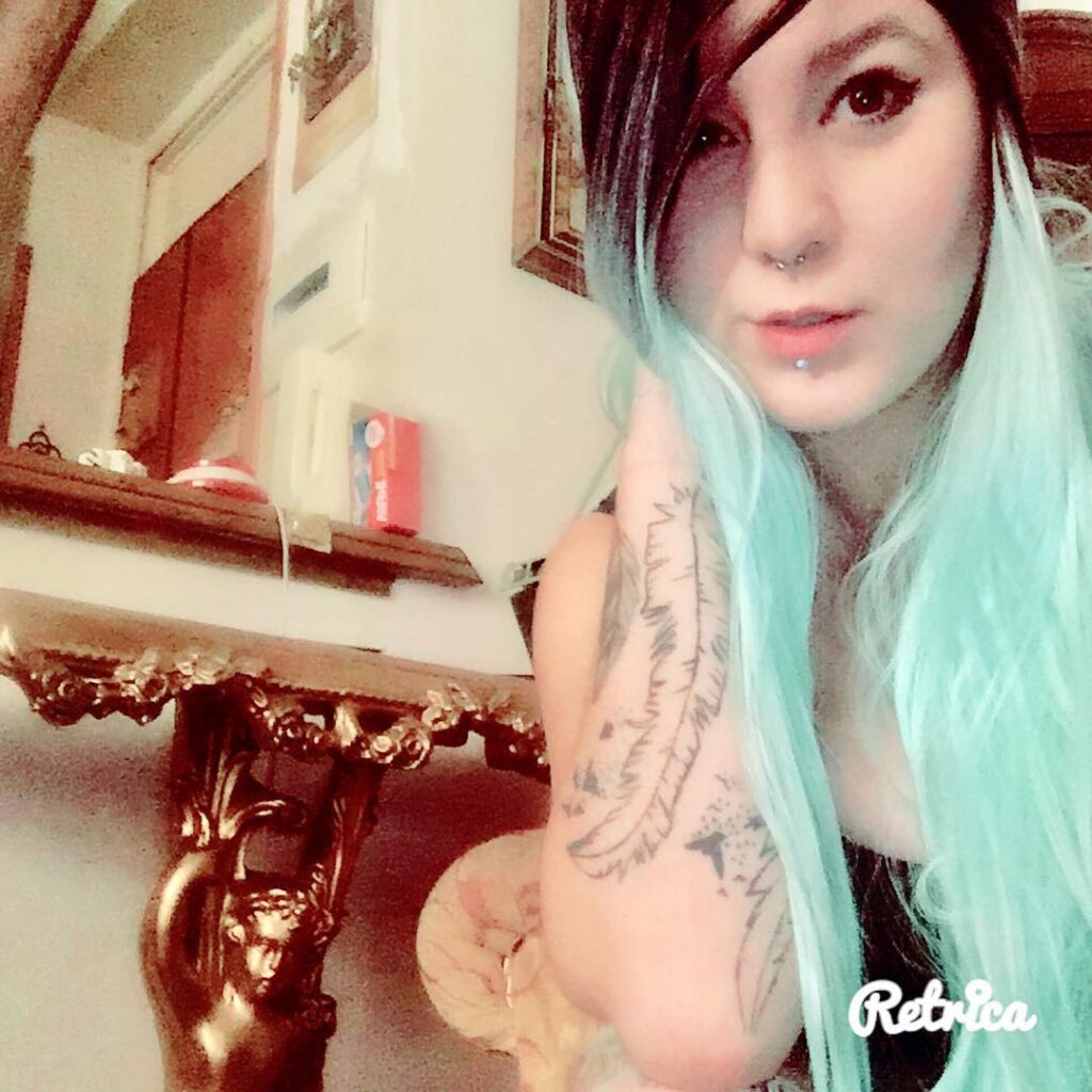 A girl sitting on the floor and posing for a selfie and showing her mint green hair color - hair color for long hair