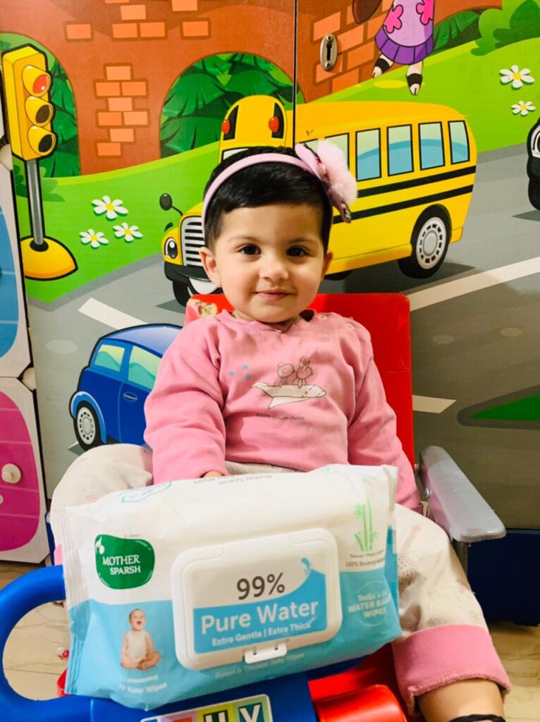 Best Baby Wipes India - Infant wears a pink t-shirt and has Mother Sparsh wipes in her hand