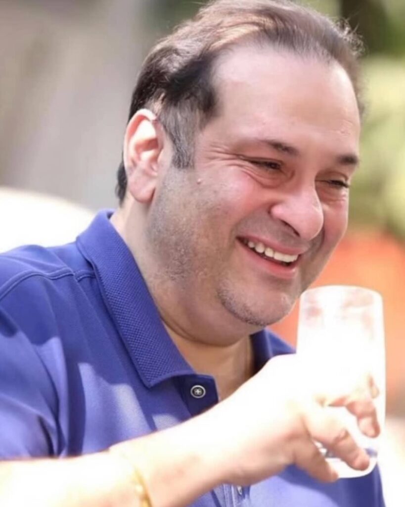 Former actor Rajiv Kapoor smiling and posing with glass - celebrity death of 2021