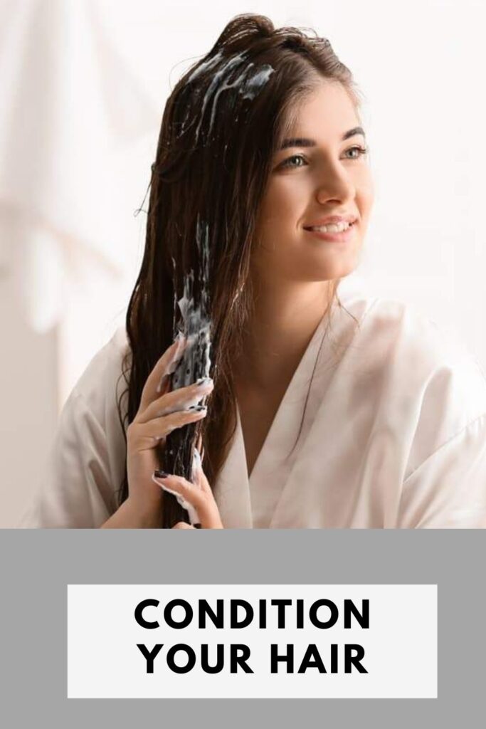 A girl is smiling and applying conditioner on her hair - grow hair faster remedies