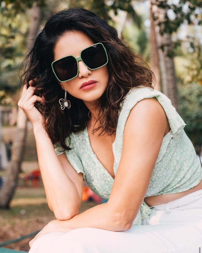 Sunny Leone in off-white cop top and goggles showing her Messy Curls -  Sunny Leone best Hairstyles