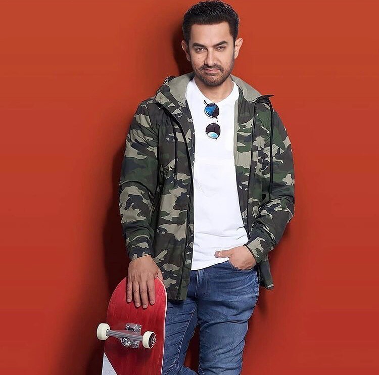 Aamir Khan in army print jacket and white shirt holding a skate board - most handsome man in India