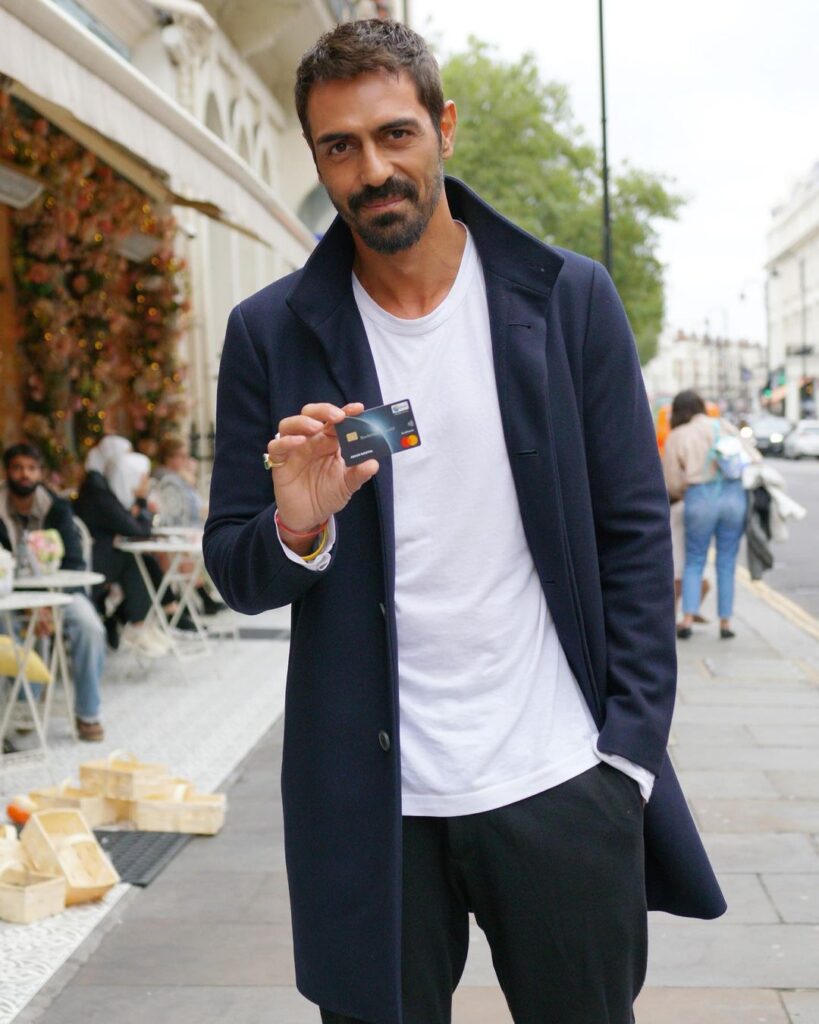 Arjun Rampal in black jacket and white t-shirt showing his card - hottest man in India