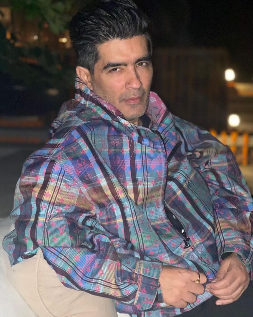 Manish Malhotra in multicolor jacket sitting and posing for camera - gay and lesbian celebrities India