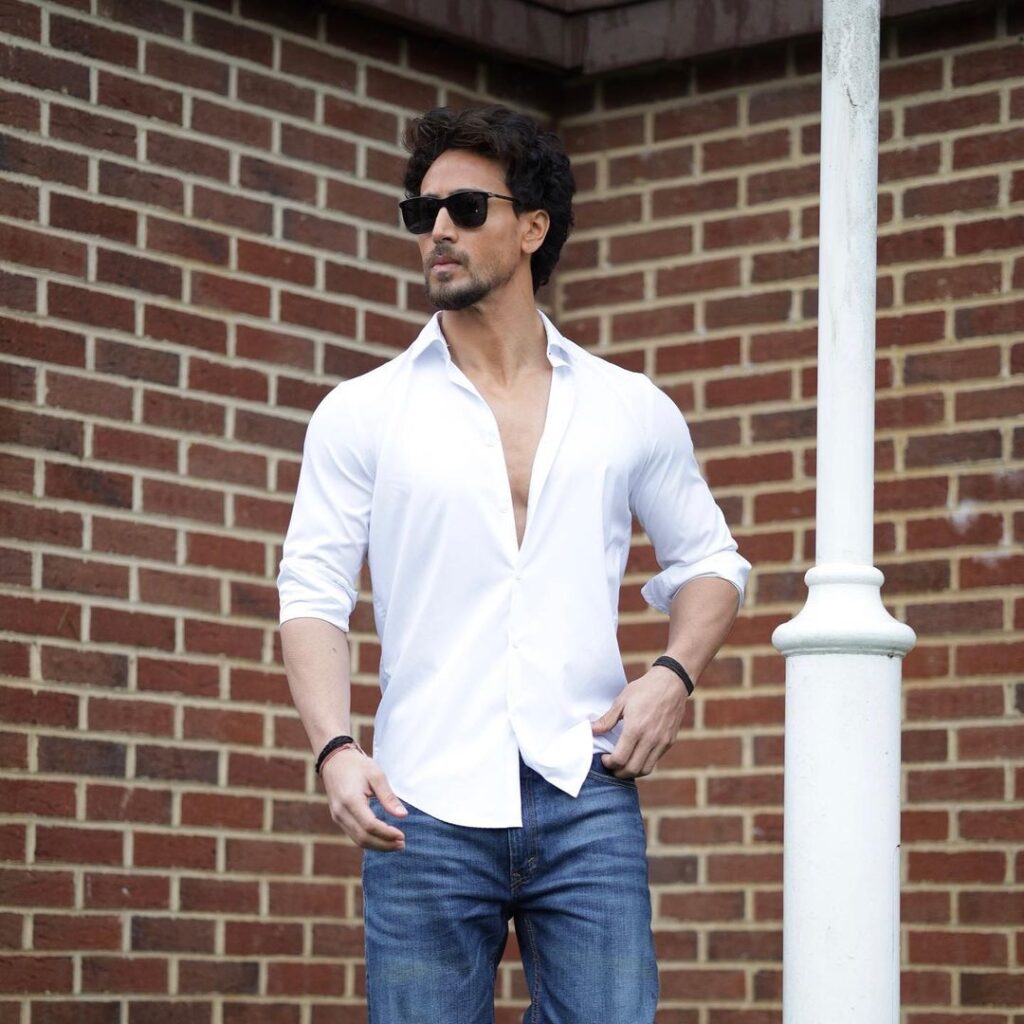 in white shirt and blue jeans Tiger Shroff is posing for camera - bollywood most handsome actor