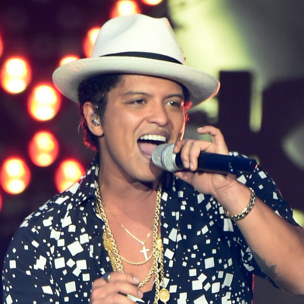 Bruno Mars in blue and white printed shirt and hat singing on stage -  short male actors of hollywood