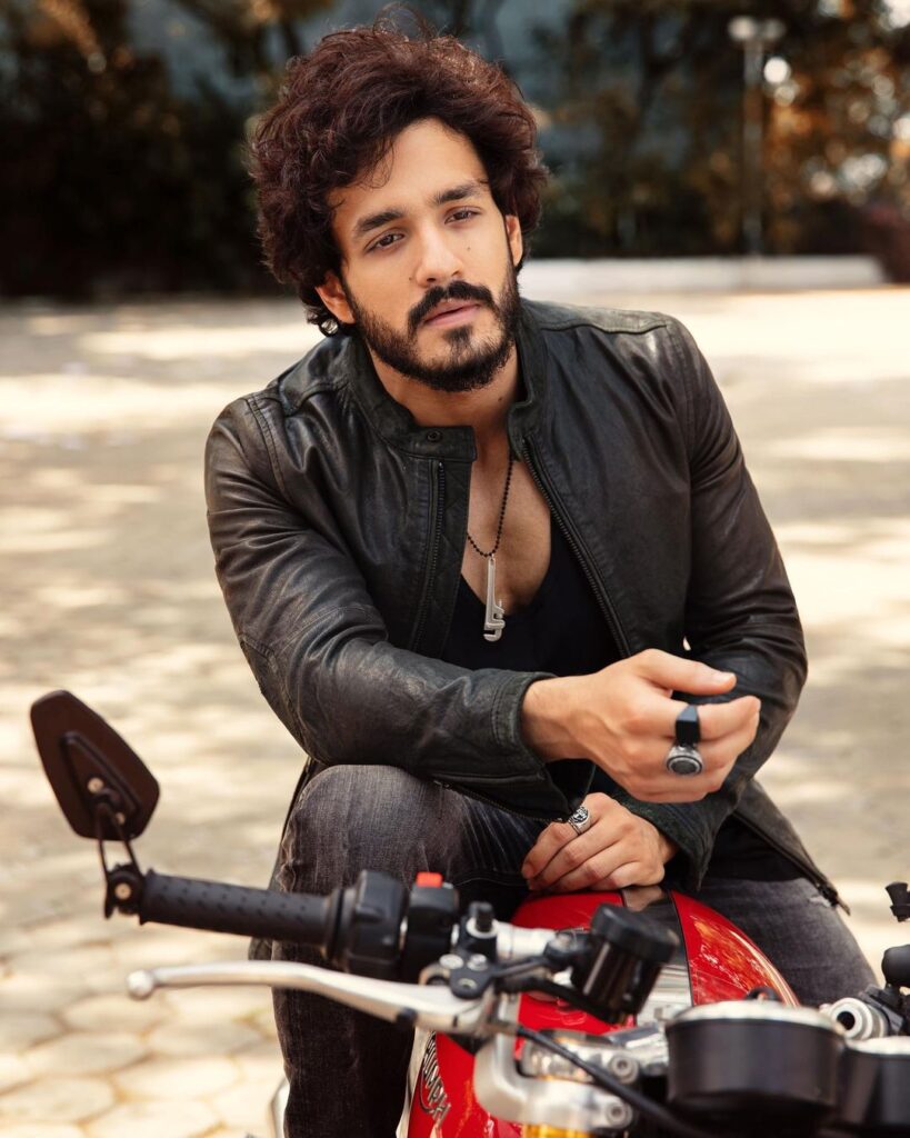 Akhil Akkineni in black leather jacket sitting on a bike and posing for camera - most handsome actors of south indian industry