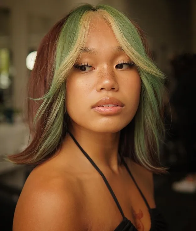 A girl in black strappy dress posing for camera and showing her Green Money Pieces hairstyle - trending hair color 2022