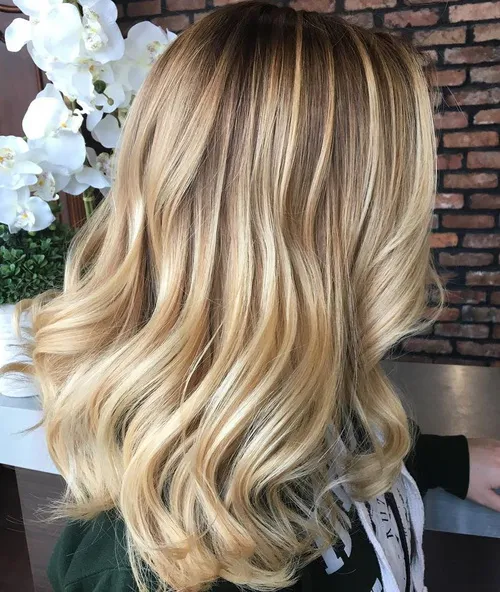 A girl in dark green top showing the side view of her Medium Blonde Balayage hair color - blonde hair color ideas 2022