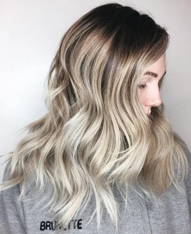 A girl in grey sweat shirt showing the side view of her Icy Blonde Ombre Waves - latest hair color 2022