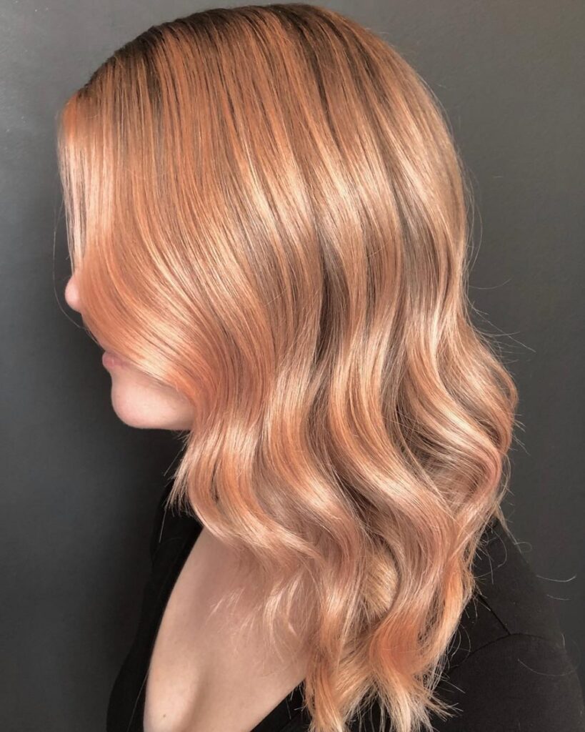 A girl in black round deep neck top showing the side view of her rose gold blonde hair color - long hair color