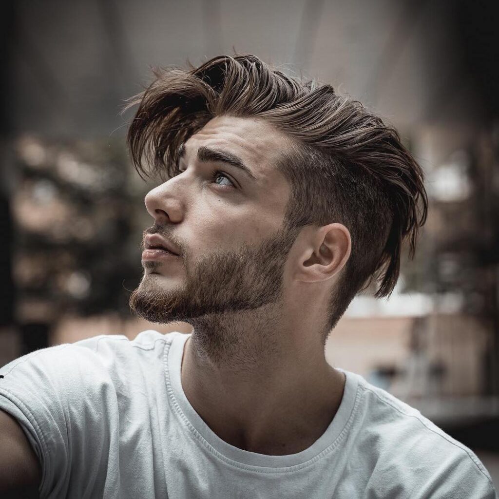 A man in white round neck t-shirt showing the side view of his Undercut With Longer Messy Hair - hairstyle for men