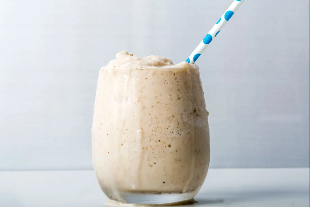 Banana Almond Cream Shake served in glass with straw - breakfast for muscle gain