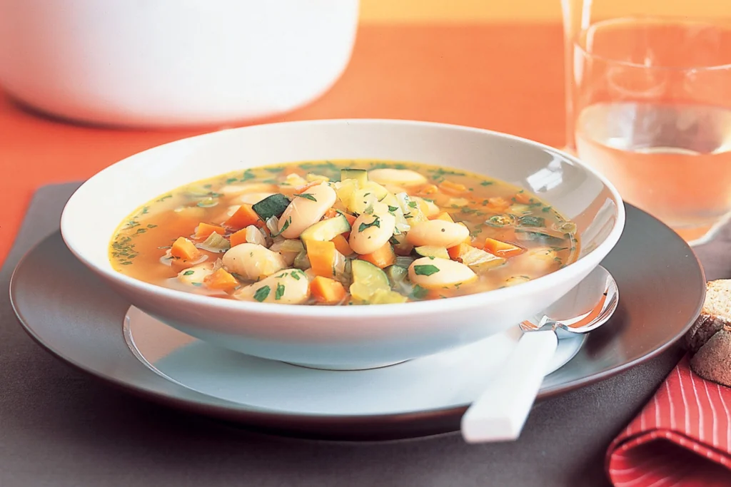 White Bean and Vegetable Soup served in a white bowl - best meal ideas for bodybuilders