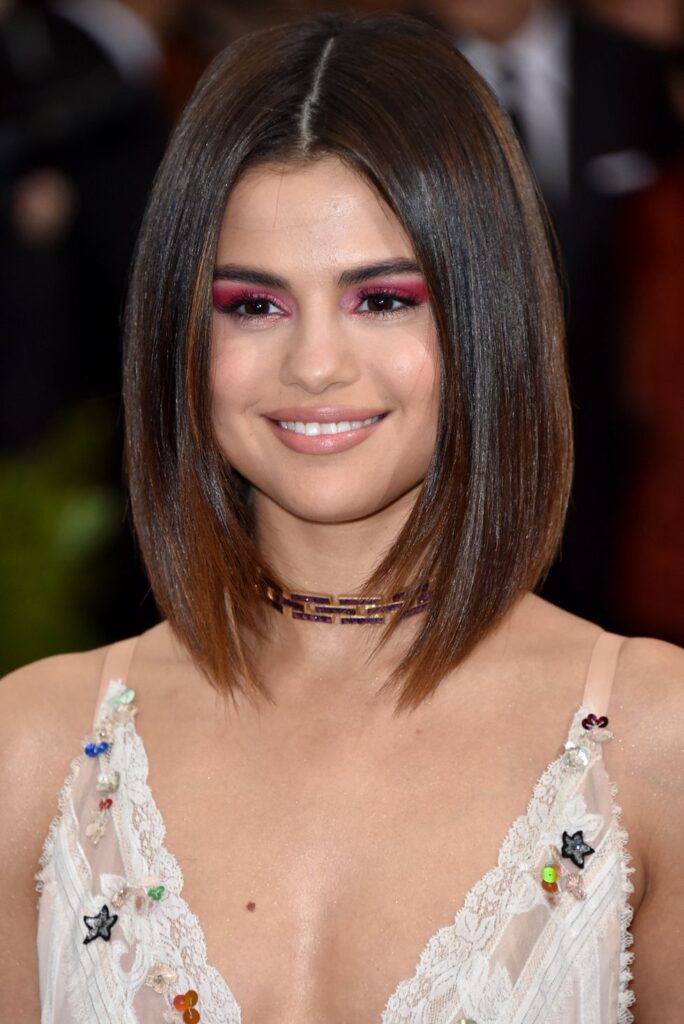 Selena Gomez in white deep neck dress posing for camera and showing her Middle Part hairstyle - selena gomez short hair