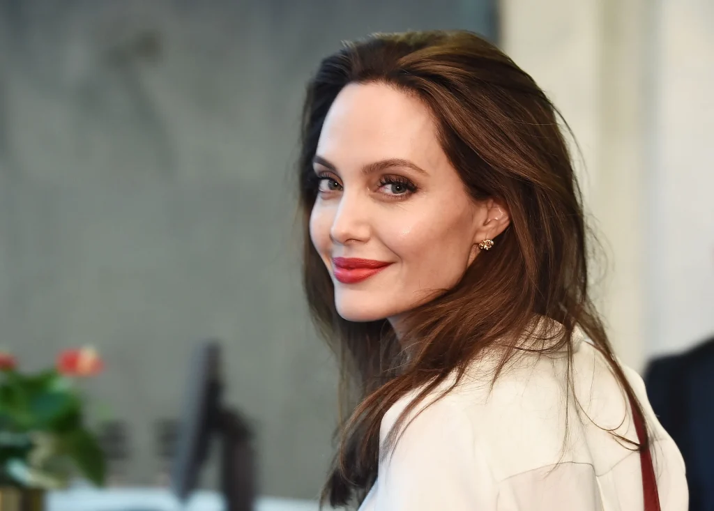 Smiling Angelina Jolie in off white shirt and pink lipstick - celebrities who got lasik