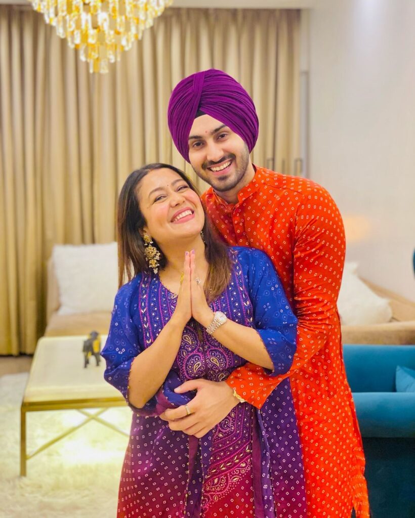 Neha Kakkar in blue suit with husband rohan preet singh in orange kurta posing for camera - hindi copule singers