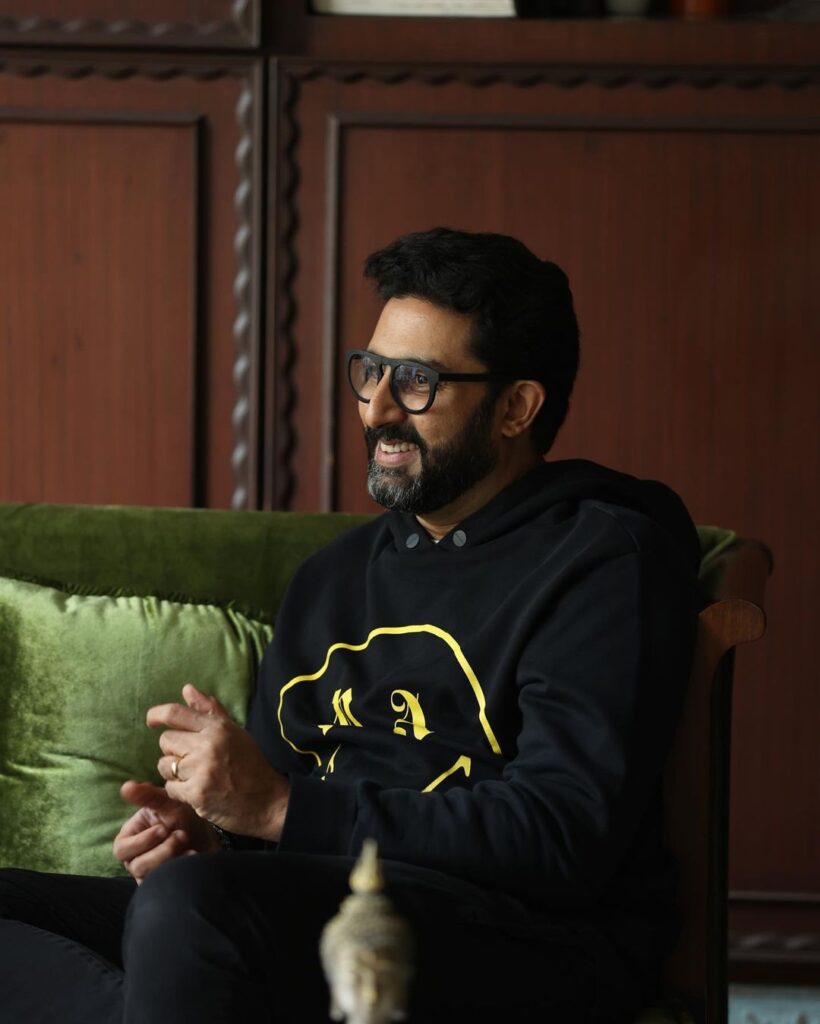 Smiling Abhishek Bachchan in black hoodie and spectacles  - bollywood actors no makeup photos