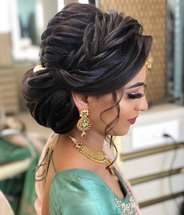 A girl in light green blouse and golden jewellery posing for camera and showing the side view of her Twisted Braided Bun - bridal hairstyles 