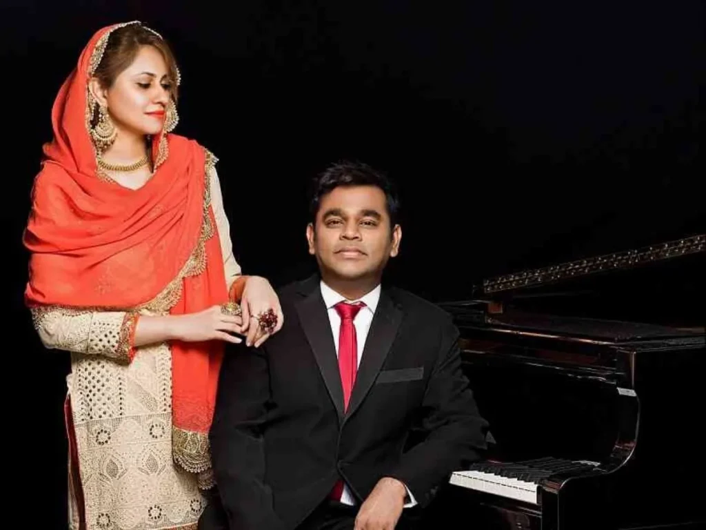 A. R. Rahman sitting in black suit and his wife Saira Banoo in off white suit with orange dupatta - Indian singers with spouse