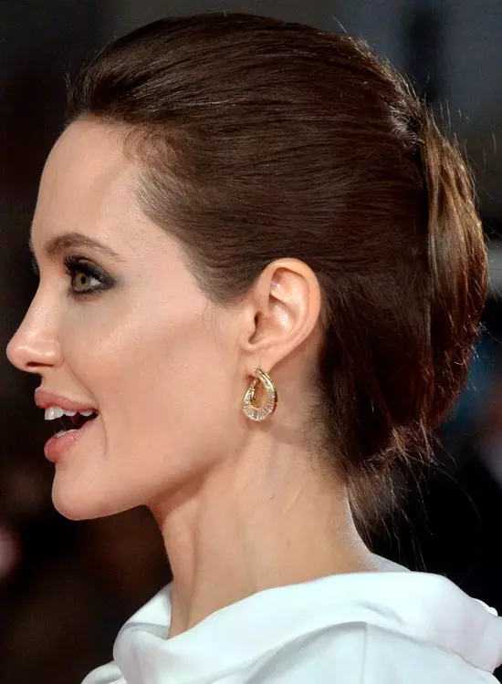 Smiling Angelia Jolie in white high neck dress and golden earring showing the side view of her sleek French Bun - hollywood actresses hairstyles
