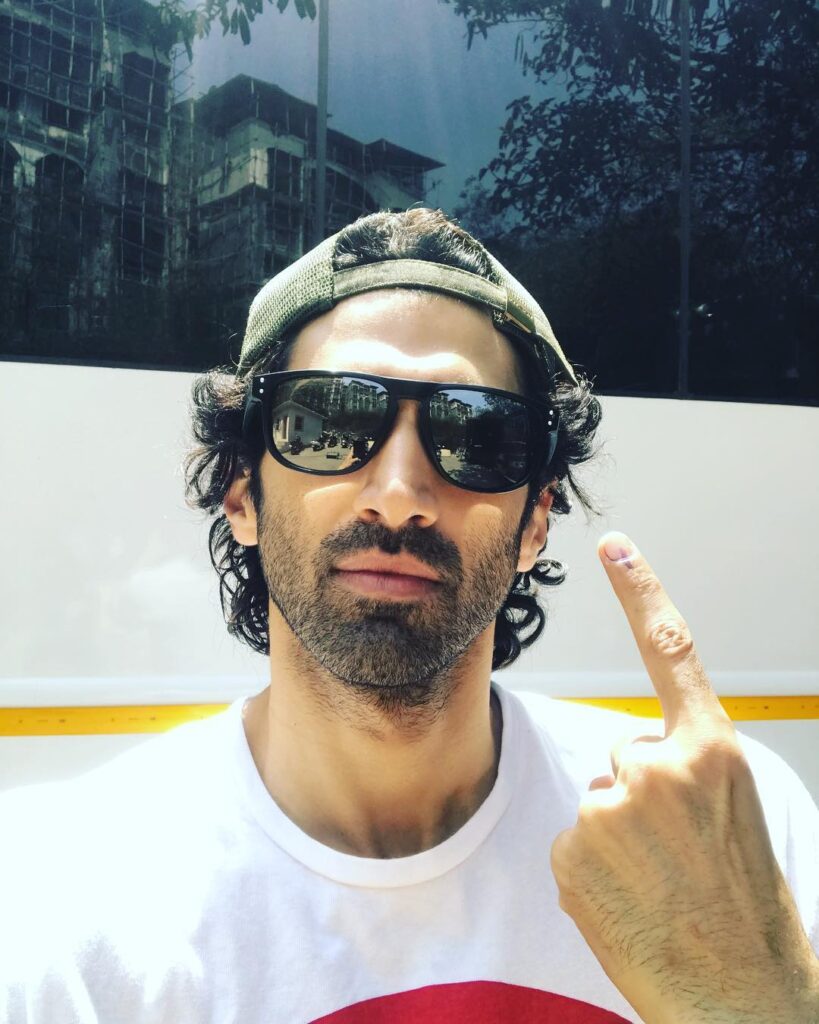 Aditya Roy Kapoor in white t-shirt with goggles and cap posing for a selfie - bollywood actors no makeup look
