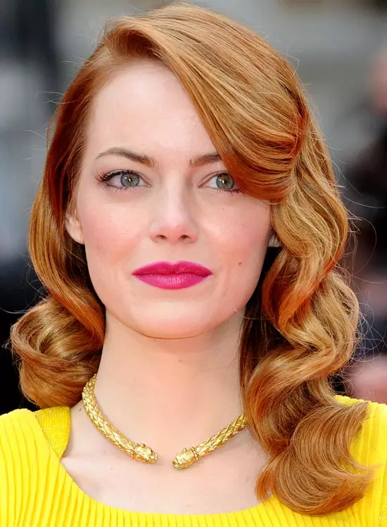 Emma Stone in yellow dress and golden necklace with hot pink lipstick posing for camera and showing her Textured Wavy Curls - actresses hairstyles