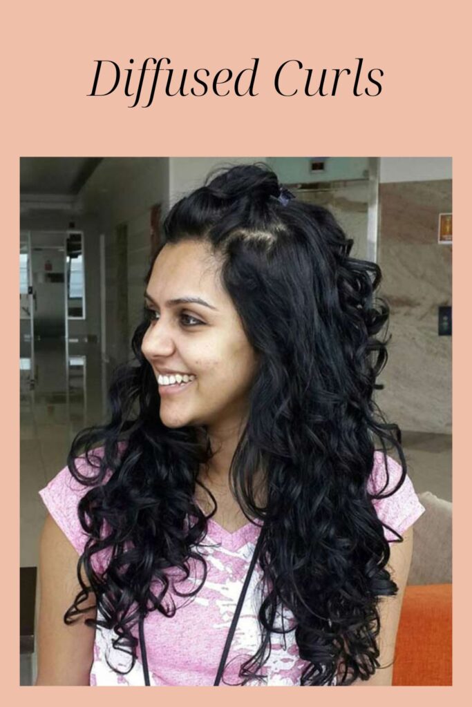 A smiling girl in pink t-shirt showing the side view of her diffused curls hairstyle - hairstyles for Indian Women