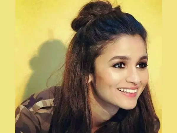 A smiling girl in army printed shirt showing her top knot bun - hairstyles for girls with medium hair