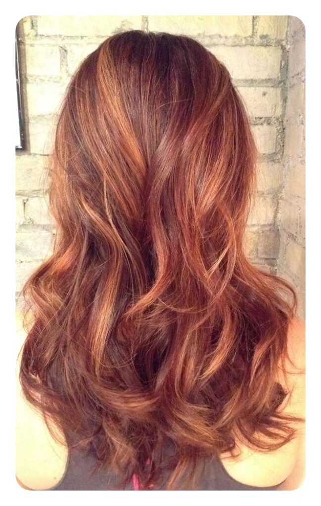 A girl is showing the back view of her red hair with highlights - red hair color ideas