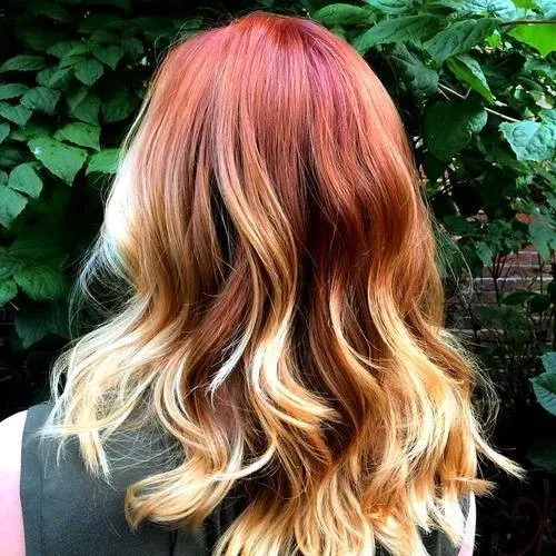A girl is showing the back view of her red hair with golden highlights - red hair color shades