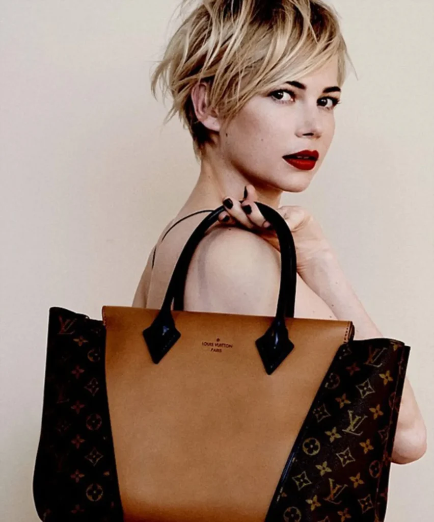 Michelle Williams in black strappy dress with red lipstick holding bag her hand - hollywood short hair actress