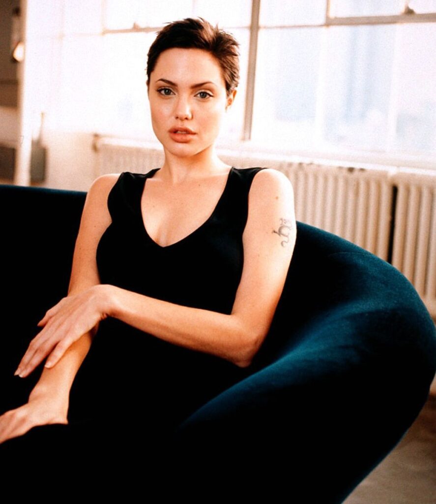 Angelina Jolie sitting on a couch wearing black tank top -  short hair hollywood celebrities