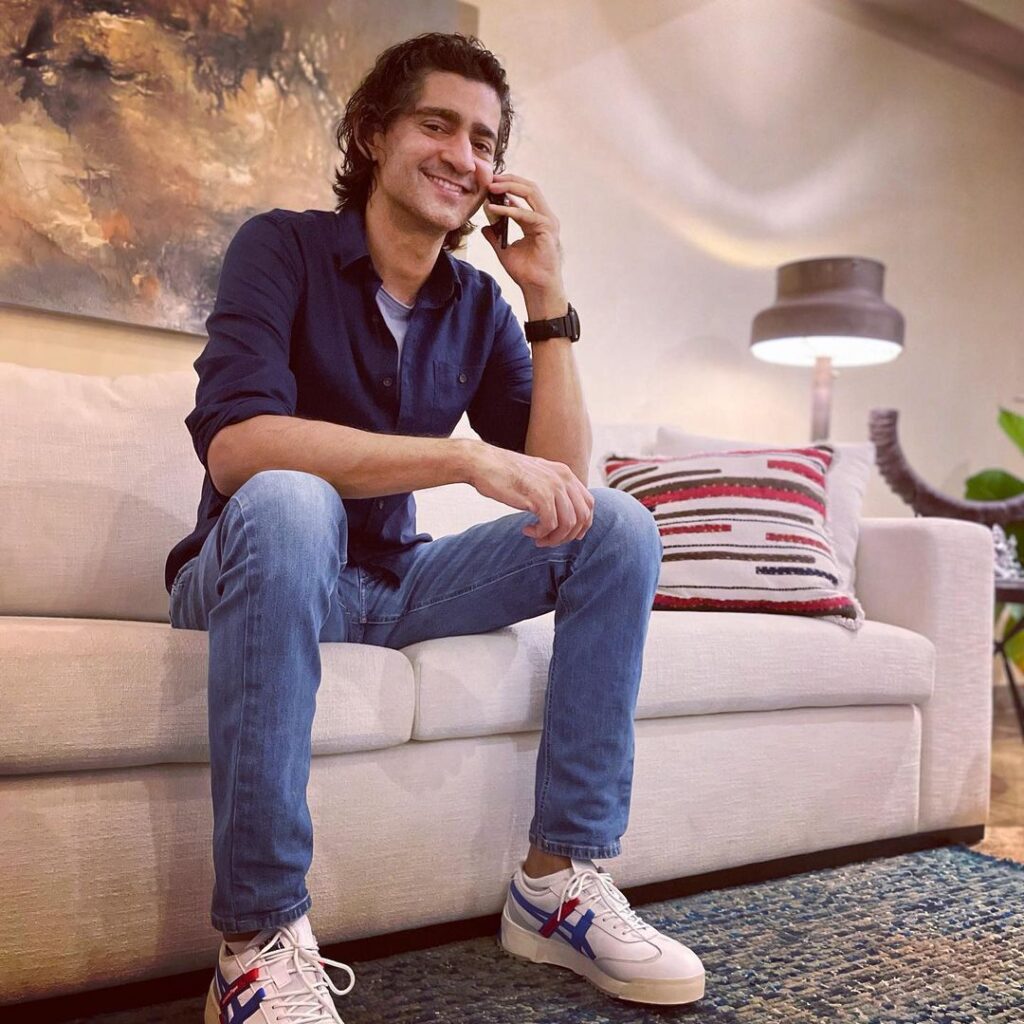 Smiling Gaurav kapoor in black shirt with blue denim and white sports shoes taking over phone - indian celebrities with diabetes