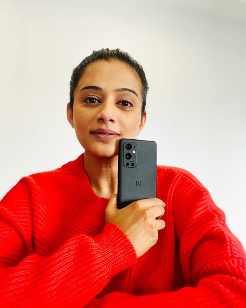 Priyamani in red sweater holding a phone ad showing her no makeup look - south actress without makeup