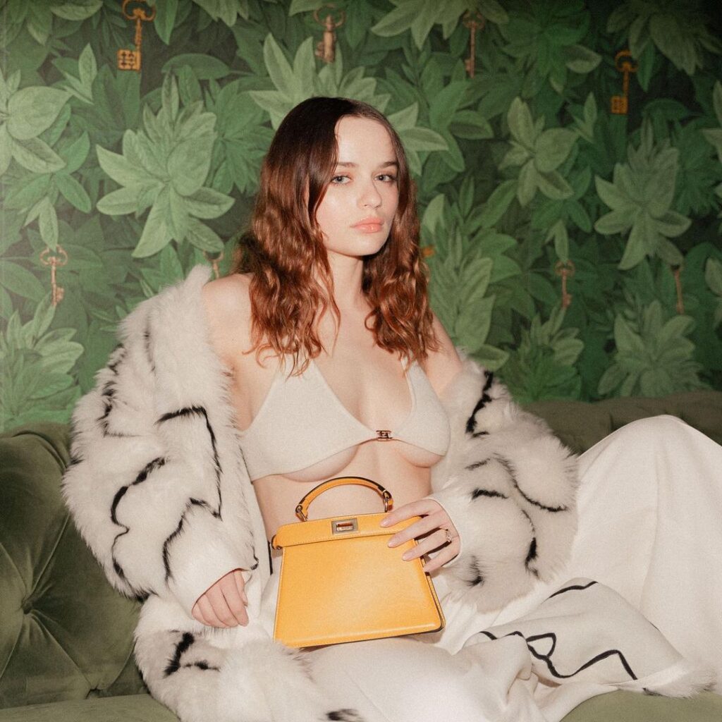Joey King in pink fur dress with yellow bag posing for camera - celebrity hairstyle