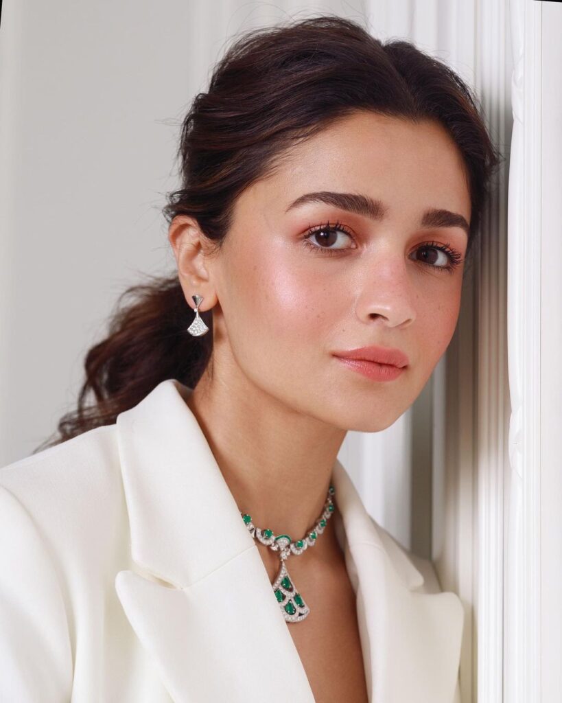 Alia Bhatt in white blazer with green necklace and matching earrings posing for camera - bollywood actress hairstyles