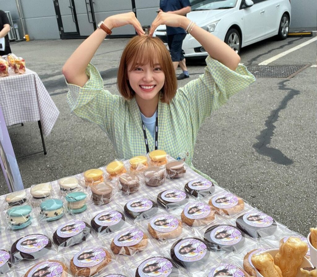 Smiling Kim Se-Jeong in green check dress posing for camera in front of a food stall - celebriity short hair cuts