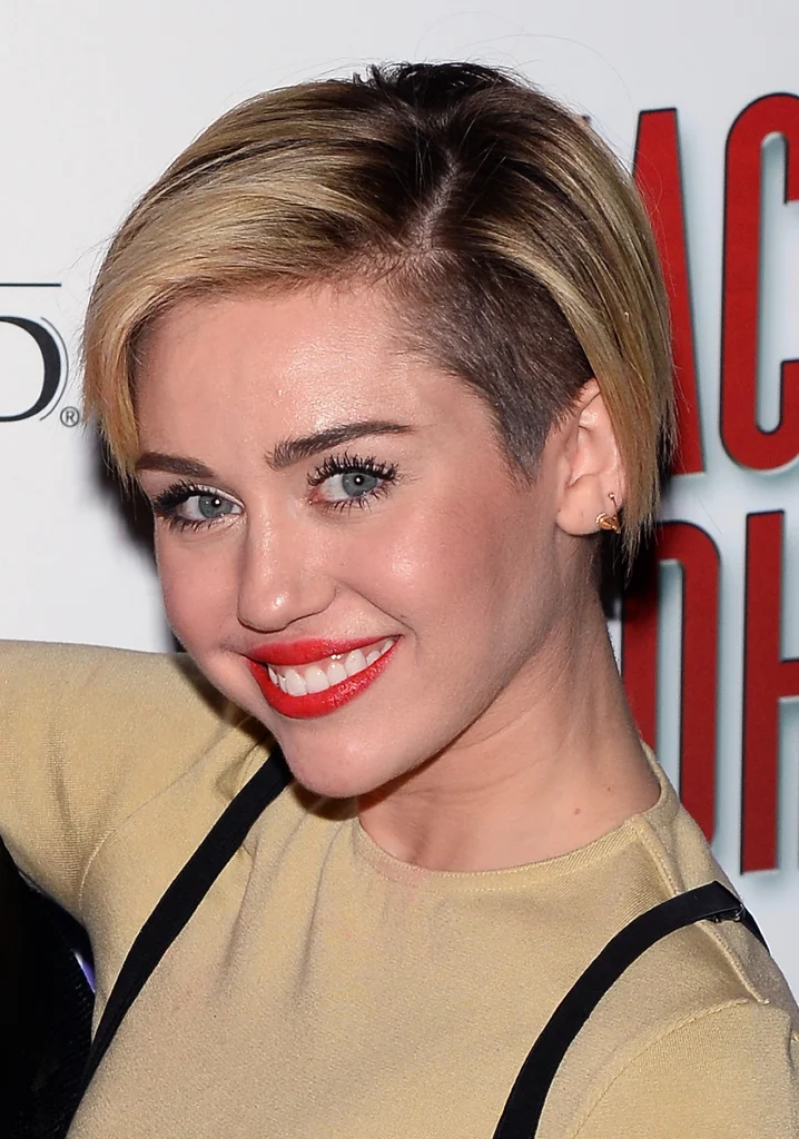 Smiling Miley Cyrus in beige dress with red lipstick posing for camera - hollywood actresses short hair