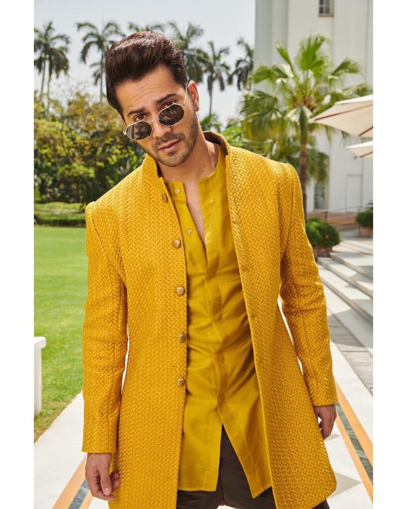 Varun Dhawan in yellow kurta and shervani with goggles posing for camera and showing his brush back faded hair - Varun Dhawan best hairstyle