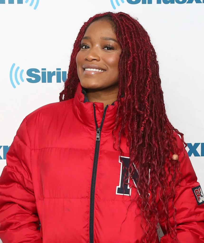 A Women in red jacket smiling and showing her Cranberry Red hair color - bright red hair color ideas